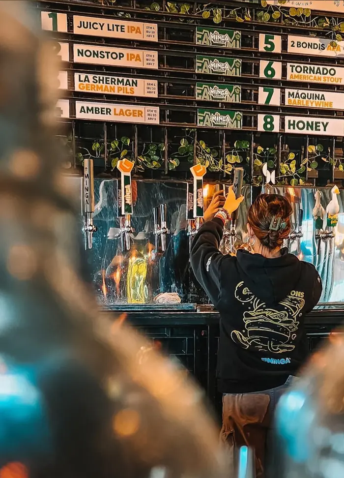 La barra de Sistons: los ocho nombres de las cervezas Minga de canilla anotados en el tablero, y alguien sirviendo una.